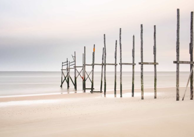 Strandpalen in het zand onderaan de duinen